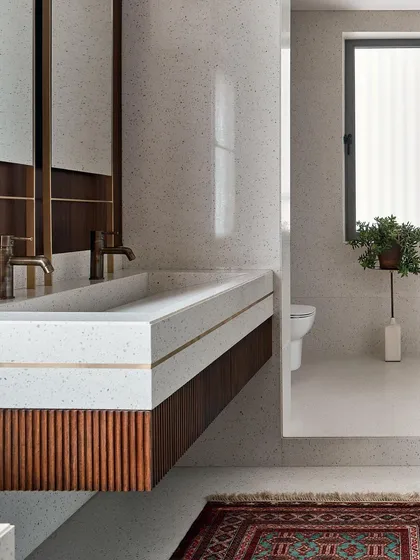 Details matter, especially in a master bathroom. Here, I used a custom terrazzo vanity with brass inlay, paired with fluted wood cabinetry and a vintage-style rug. It's a blend of modern materials and classic textures for a timeless appeal.