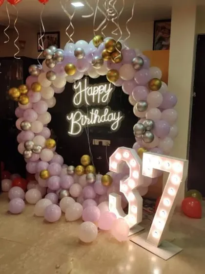 A circular balloon arch with a 'Happy Birthday' neon sign and marquee numbers, perfect for milestone birthdays.