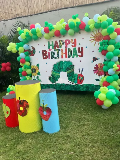 A "The Very Hungry Caterpillar" themed birthday backdrop. This classic storybook theme is brought to life with colorful balloon art and character cutouts.