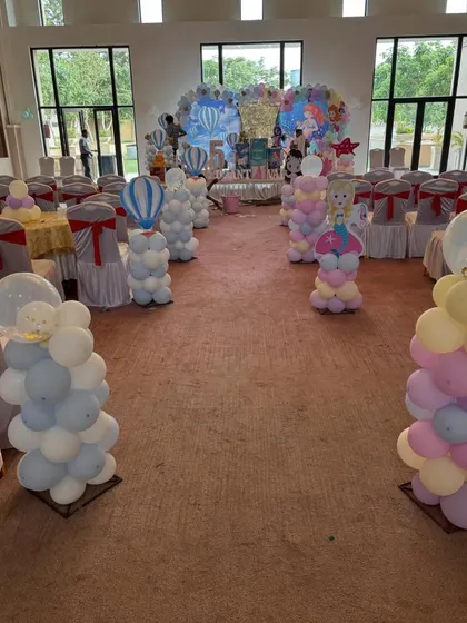 This image shows the full party hall decorated for the twin's birthday, with themed balloon pillars lining the aisle.