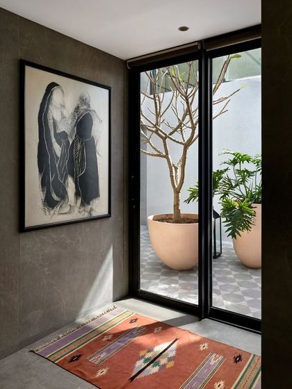 Another view of a passage in the Mango Orchard House, where a large piece of art is juxtaposed with a view into a sunlit courtyard, blending art and nature.