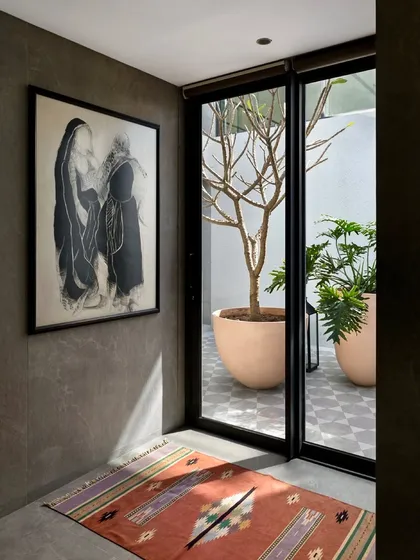 A piece of art hangs in a hallway that opens onto a courtyard, blending the boundaries between interior gallery and exterior garden. The design ensures that even transitional spaces are filled with light and art.