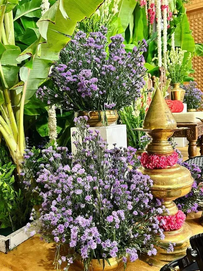 The combination of purple and white flowers with traditional brassware creates a visually stunning and harmonious decor palette.