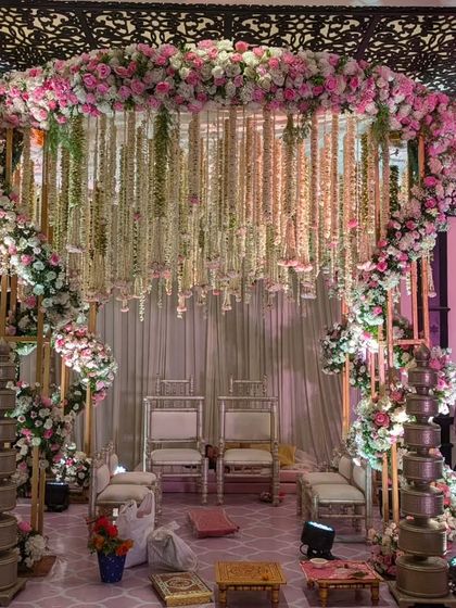 This circular mandap is designed for an intimate yet grand ceremony. A ring of pink and white florals is suspended overhead, with delicate floral strings cascading down, creating a romantic and ethereal space for the vows.