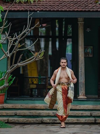 The groom, dressed in a traditional veshti, strides confidently through the property.