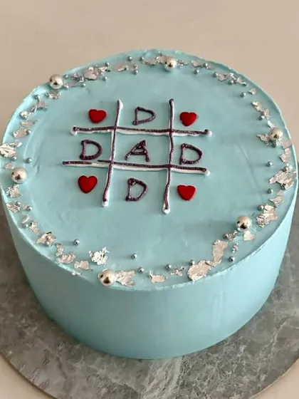 A side view of the Father's Day tic-tac-toe cake, showing the clean finish and silver leaf details.