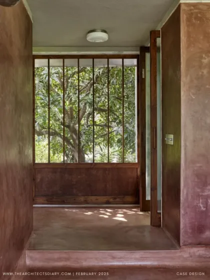 A view through a doorway at Villa Uma, where the dappled light filters through a large mango tree. The architecture is designed to frame the landscape, making the natural surroundings a constant feature of the interior experience.