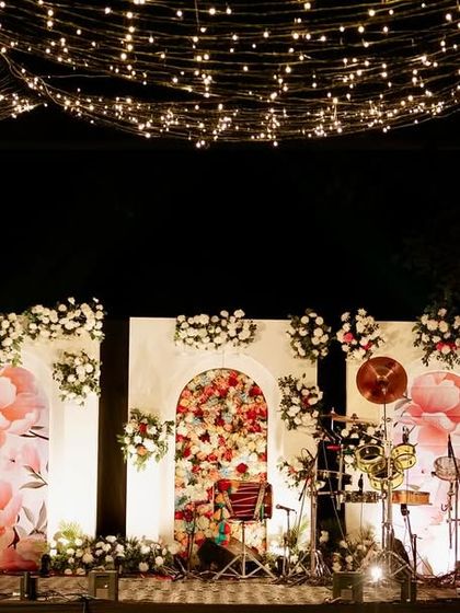 The performance stage for the Sangeet, set under the fairy light canopy, with a beautiful floral-printed backdrop.