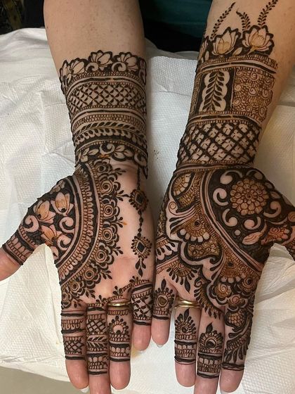 This designer mehndi plays with asymmetry. One hand has a dense floral pattern, while the other features a lighter, more open design with a central mandala, offering a unique and modern look.