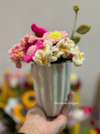 A small, handheld bouquet of pink and white crochet daisies. These are perfect for small vases or as a charming gift.