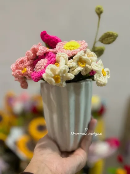 A small, handheld bouquet of pink and white crochet daisies. These are perfect for small vases or as a charming gift.