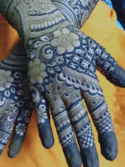 A close-up of the palms, showing extremely fine and detailed floral and geometric work. The dark paste promises a beautiful stain.