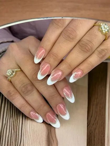 A perfect example of a modern French manicure. I created this elegant look with crisp white tips on an almond-shaped nail, enhanced with a delicate line of silver glitter for a touch of sparkle.