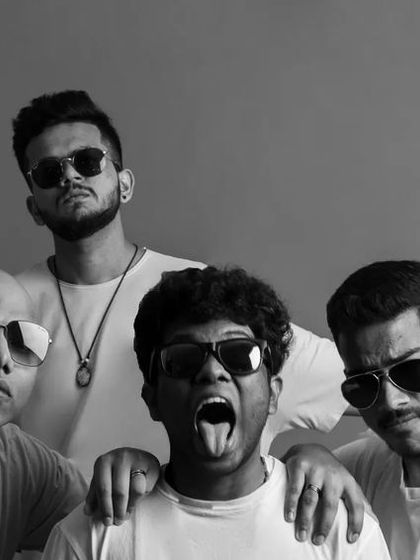 A stylized black and white group portrait of the band. This image has a completely different mood, showcasing a cooler, more serious, and fashion-forward side to their persona.