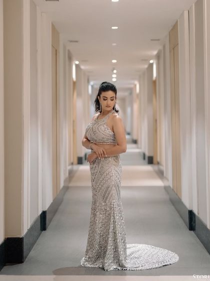 A full-length portrait of the bride in a corridor, her glittering gown trailing behind her.