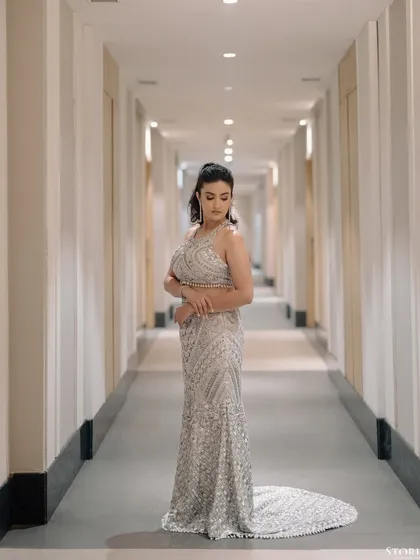 A full-length portrait of the bride in a corridor, her glittering gown trailing behind her.