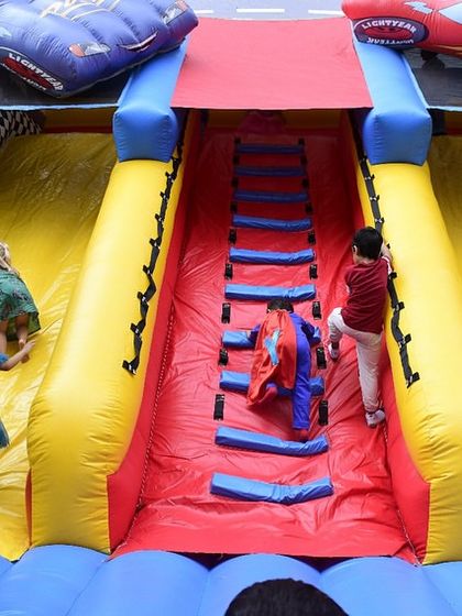 Kids climbing and sliding on the inflatable, a perfect activity for an outdoor party. I ensure all equipment is set up safely and supervised.
