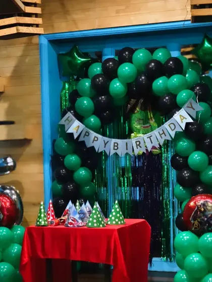 A simple and clean green and black balloon arch, ideal for a superhero or gaming-themed birthday party.