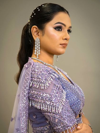 A side profile showing the elegant ponytail hairstyle with pearl details, a great way to style this modern rental lehenga.