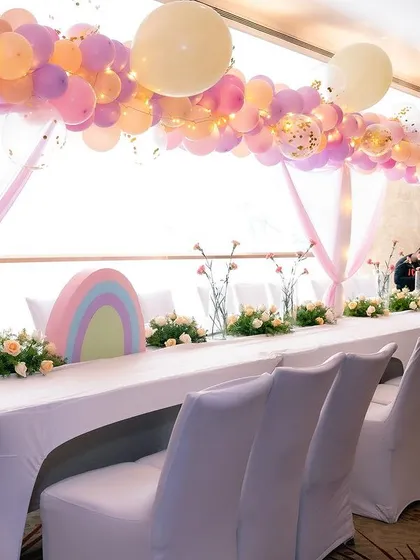 The long guest table at the unicorn party, decorated with a pastel balloon arch and floral runners.