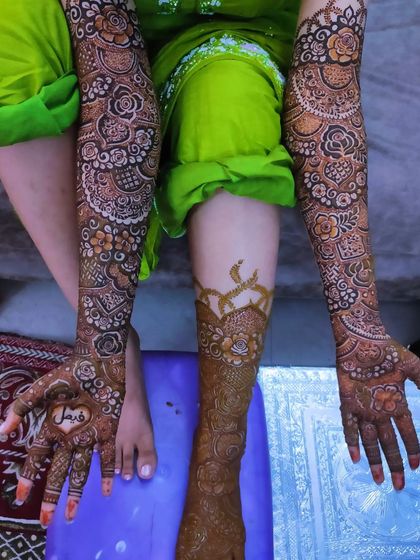 A lovely bridal design with the groom's name, 'Faisal', written inside a heart on the palm.