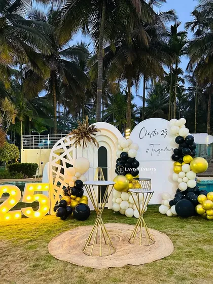 Celebrating "Chapter 25" with a stylish poolside setup. The combination of marquee numbers, a modern white backdrop, and a black and gold balloon garland is perfect for milestone birthdays.