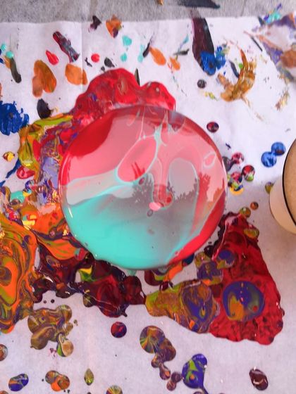 A coaster mid-pour, sitting on a wonderfully messy surface. This image captures the playful and experimental nature of my fluid art workshops.
