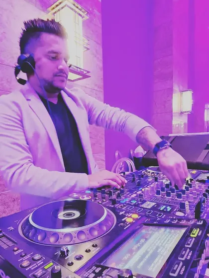 A shot of me mixing at an indoor event. The purple uplighting and my expression show the focus and passion I bring to every single gig.