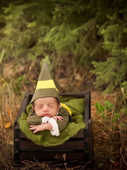 This little one, dressed as a woodland elf, sleeps in a wooden crate in a digitally created forest, ready for a magical adventure.