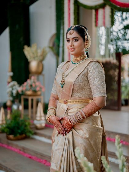 A bride stands gracefully in her golden silk saree and matching blouse. The simple gold belt adds a modern touch to this otherwise traditional and classic ensemble.