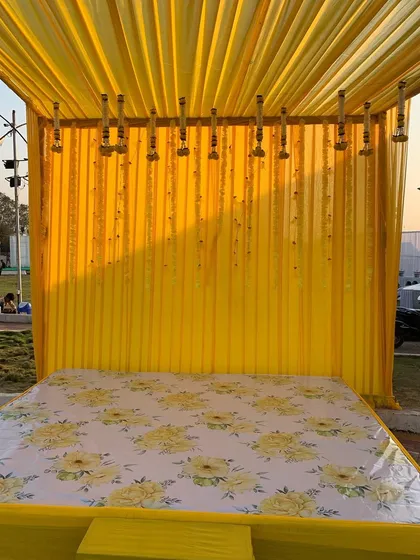 A simple and budget-friendly Haldi backdrop. I used yellow drapes and hanging garlands of marigolds and white flowers to create a traditional and elegant setting.