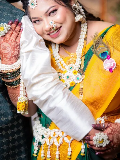 A sweet moment captured at a baby shower. You can see the details of the floral kamarband, bajuband, and the personalized 'Aai' brooch with a peacock feather.