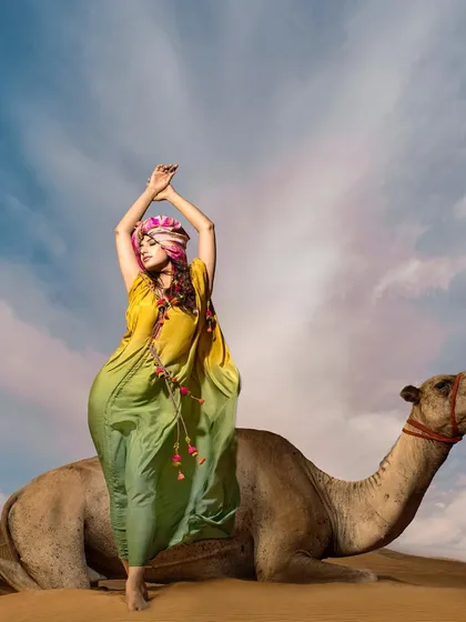 A playful and majestic pose from the kaftan series in the desert. This shot tells a story of confidence and connection with the vast, beautiful landscape.