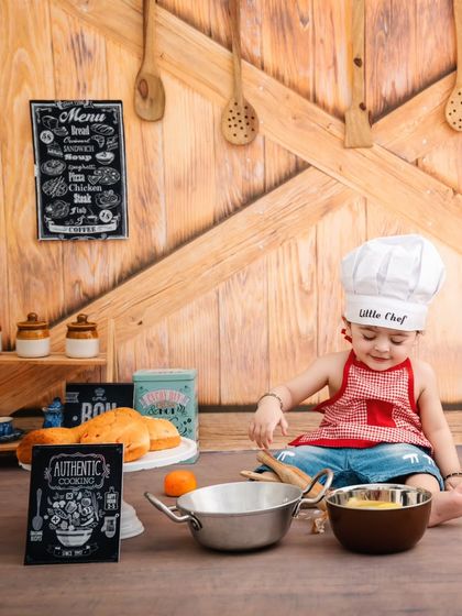 This little chef is taking a break from cooking to flash a charming smile, surrounded by all his kitchen tools.