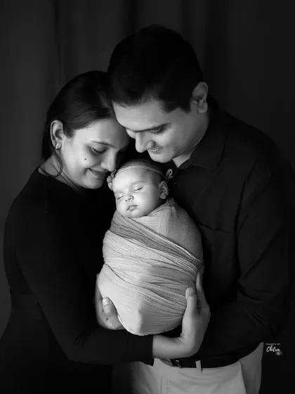 This black and white version of a family portrait feels incredibly intimate and classic. It highlights the soft expressions and the deep connection between the new parents and their baby.