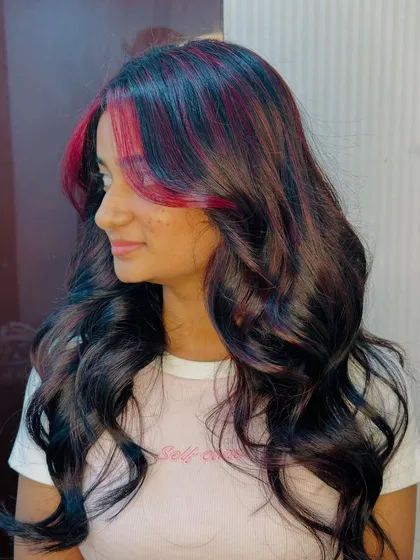 The side profile of the cherry red highlights shows how they blend with the dark hair for a striking contrast.