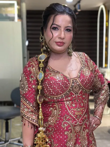 A front-facing view of this elegant party look. The makeup enhances her features beautifully, and the traditional hair accessory adds a festive touch to her braided hairstyle.