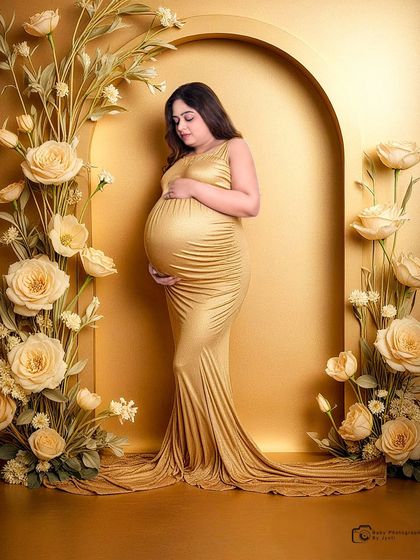 A radiant solo portrait in a shimmering gold gown. The golden archway and matching flowers create a luxurious and warm setting for this maternity photo.
