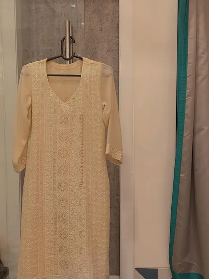 A full view of our elegant cream Chikankari kurta hanging in our studio. The sheer sleeves and detailed embroidery make it a light and sophisticated choice for any occasion.