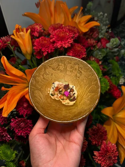 An Asian-inspired appetizer held against a backdrop of vibrant flowers, showcasing our commitment to beautiful presentation.