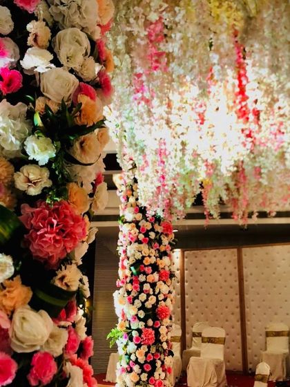 This shot highlights the rich texture and detail of my floral work. You can see the variety of flowers like roses and carnations in different colors packed together on the mandap pillars, with a canopy of hanging blossoms above.