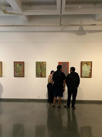 A group of visitors looking at the works of Unnikrishnan C.