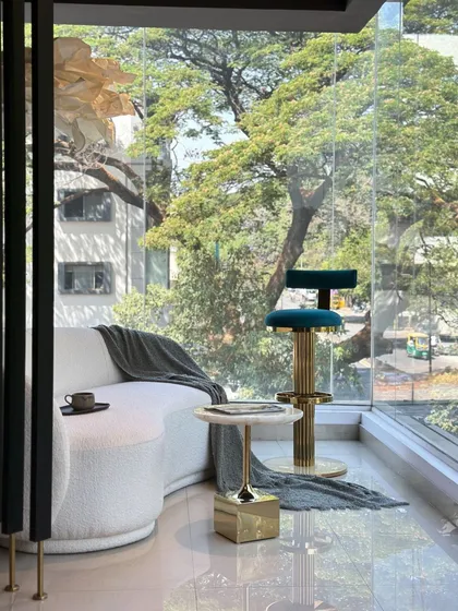 This view of my studio's display area shows how I curate pieces to create a cohesive, luxurious atmosphere. The space features a custom curved boucle sofa, a fluted PVD gold bar stool in teal velvet, and a marble side table, demonstrating a complete design vision.
