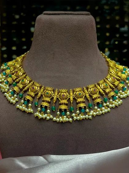 A beautiful temple jewellery choker with green beads and pearls. This type of short necklace is perfect to layer with a longer haar for a complete South Indian bridal look.