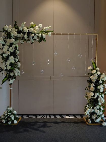 This is a simple and modern photo backdrop we created. It features an asymmetrical white floral arrangement on a gold frame, with hanging crystal strings that catch the light beautifully.