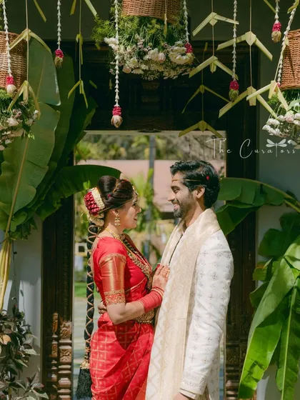 A beautiful moment captured. The decor, featuring hanging floral baskets and banana leaves, creates a perfect, traditionally rooted frame for the happy couple on their special day.