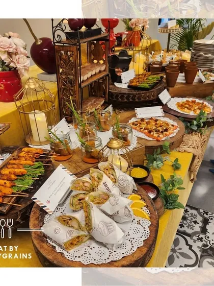 A warm and inviting grazing table setup with a yellow theme. This spread features a mix of Indian and continental appetizers, including pizzas, wraps, and skewers, perfect for a relaxed house party.