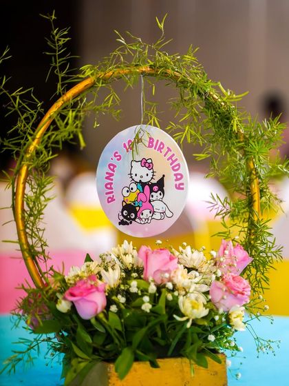 An elegant floral centerpiece with a hanging Hello Kitty themed birthday medallion.