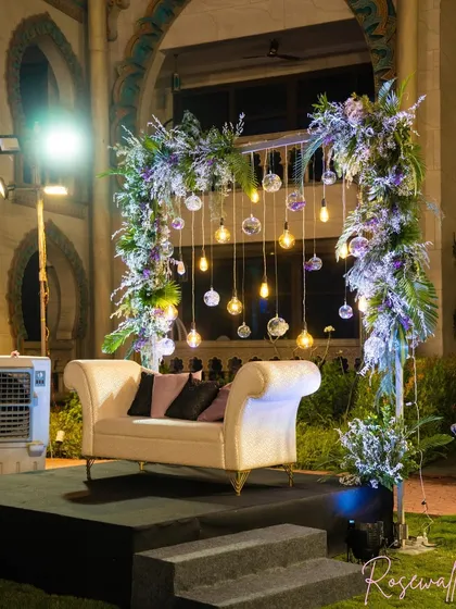 A beautifully designed photo booth or intimate seating area, framed with lush florals and hanging lights, providing a perfect spot for pictures.