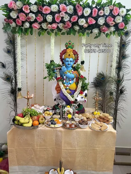 A beautiful setup for Krishna Janmashtami, including a floral canopy with peacock feathers and a table for offerings.